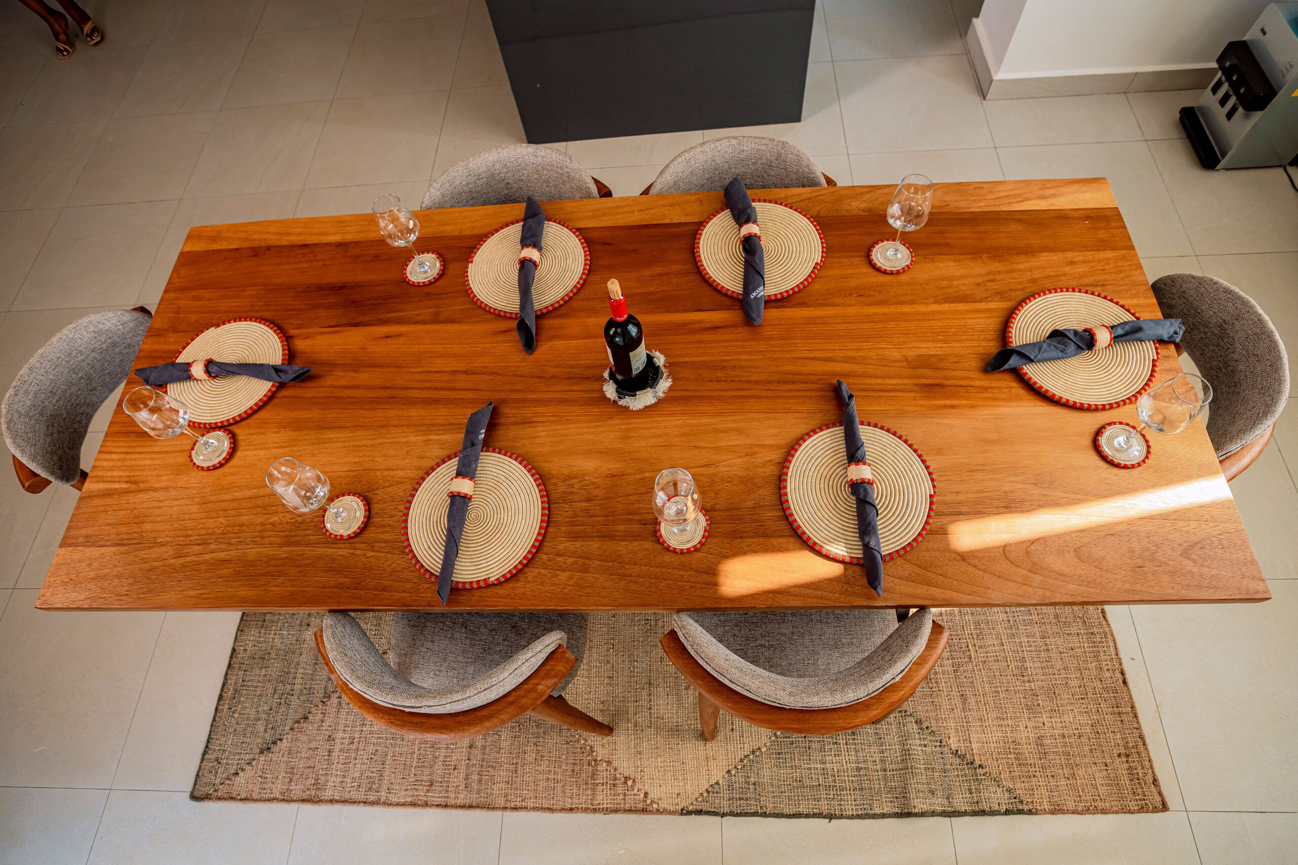 Dining table styled with handcrafted placemats, coasters, napkin rings, and woven centerpiece by Irebe Basket Collection.