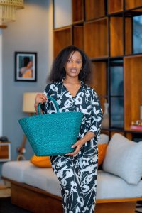 A woman holding a teal handcrafted raffia handbag from Irebe Basket Collection.